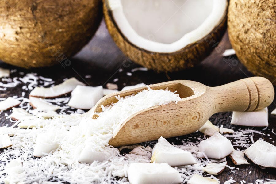 Coco ralado branco em concha de madeira com cocos frescos