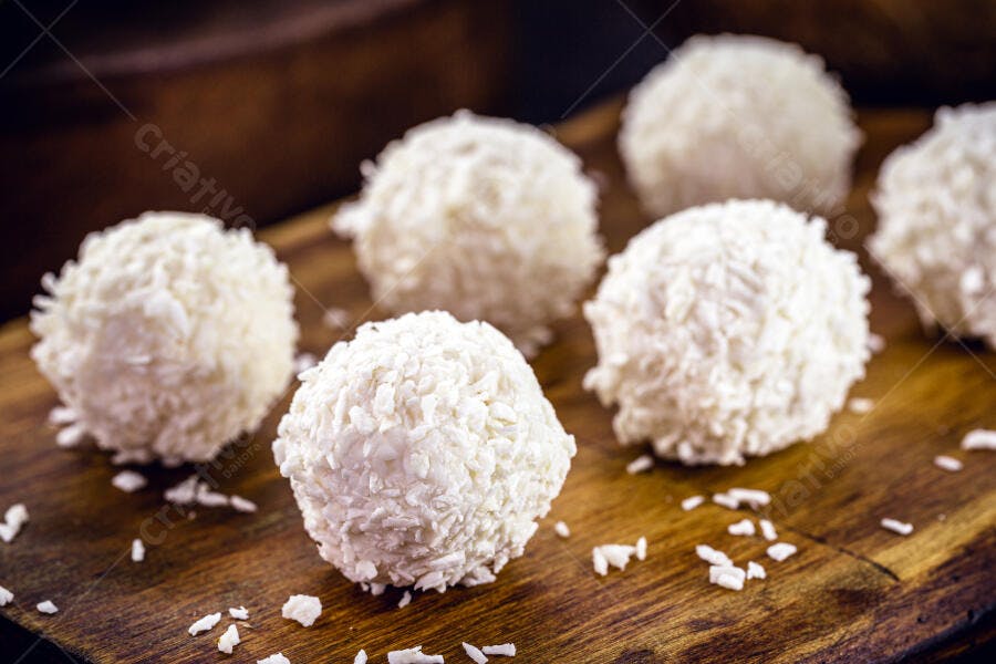 Beijinhos de coco brancos sobre tábua de madeira rústica doces brasileiros