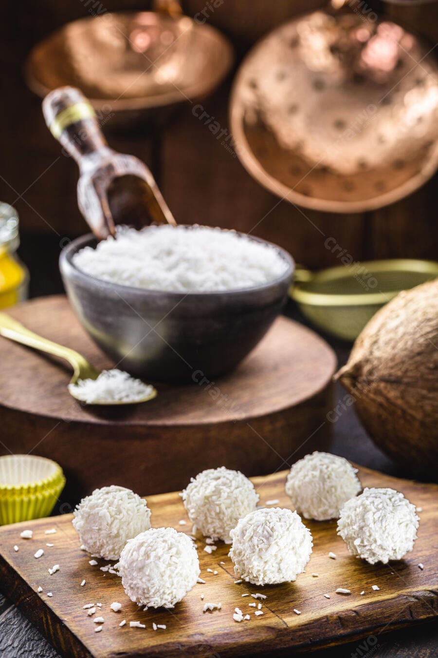 Beijinhos de coco doces brancos em tábua de madeira rústica com coco fresco
