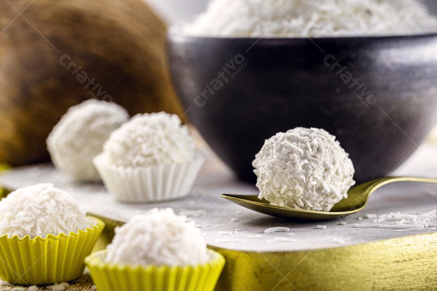 Doces de coco beijinhos brasileiros em forminhas amarelas e brancas