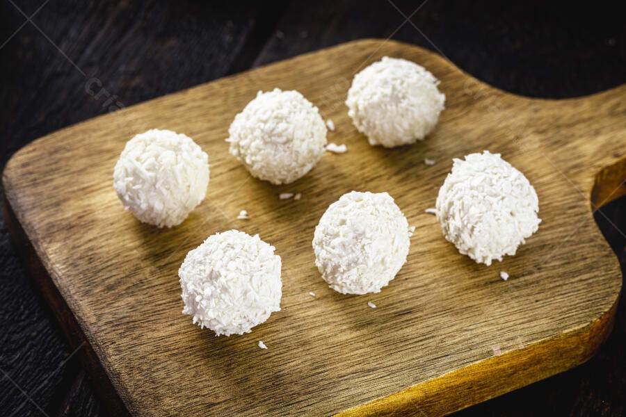 Beijinhos de coco brancos doces sobre tábua rústica de madeira