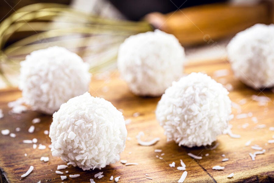 Beijinhos de coco brancos em tábua rústica festa de aniversário