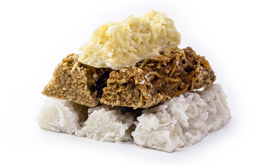 Pilha de cocadas brasileiras brancas e caramelizadas sobre fundo branco
