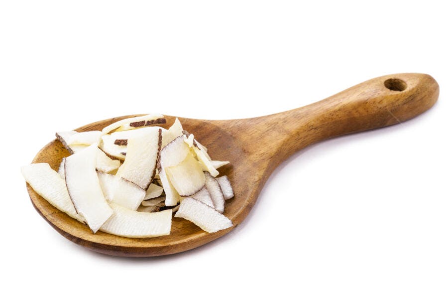 Flocos de coco tostados crocantes em colher de pau isolados no branco