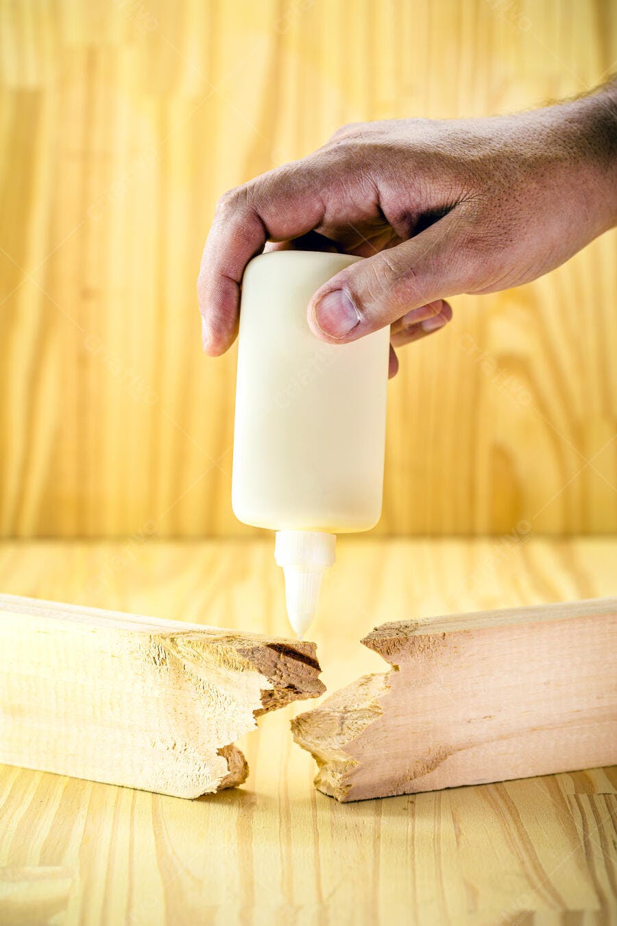 Mão aplicando cola de madeira em pedaços quebrados para conserto DIY