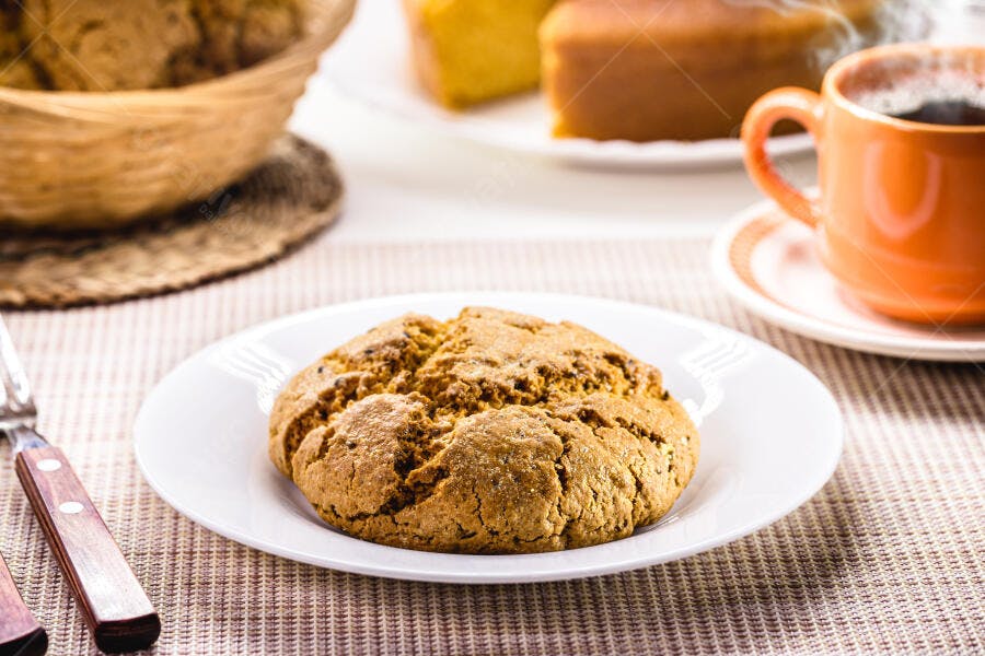 Broa de milho caseira e café quente servidos com bolo de fubá em mesa rústica