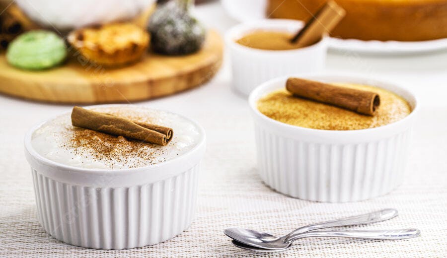 Arroz doce cremoso e pudim dourado com canela em ramequins brancos