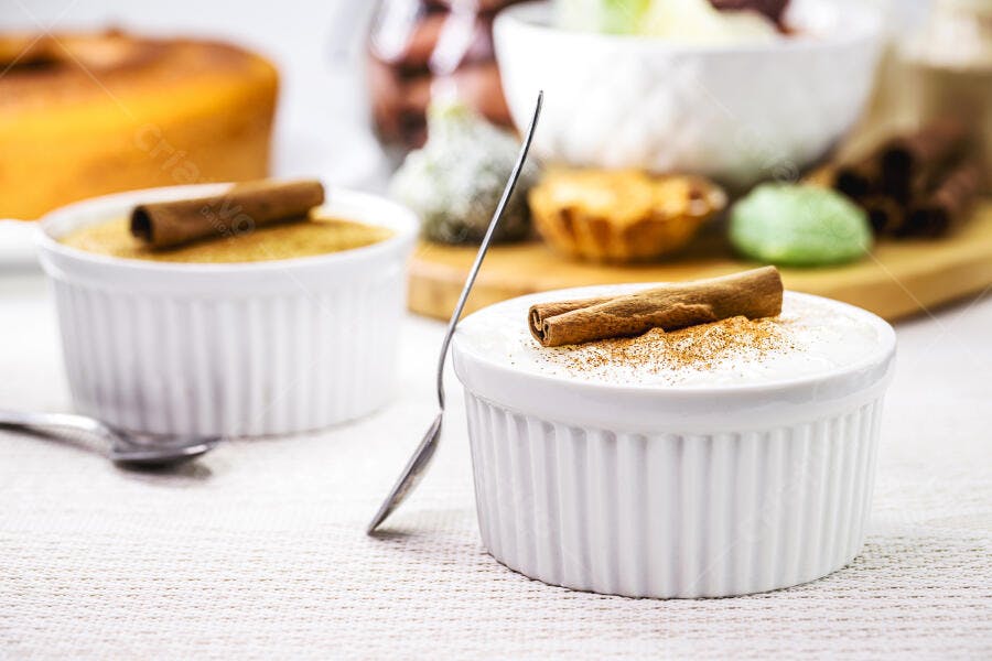 Arroz doce cremoso com canela em ramequins brancos sobre mesa rústica clara