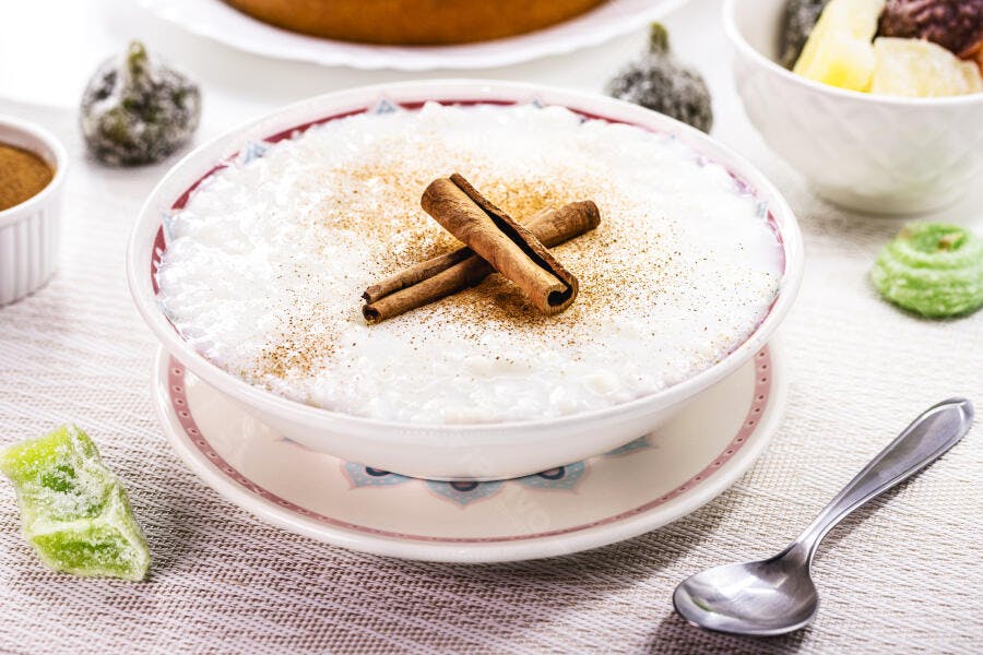 Arroz doce branco cremoso com canela em tigela tradicional sobre mesa festiva