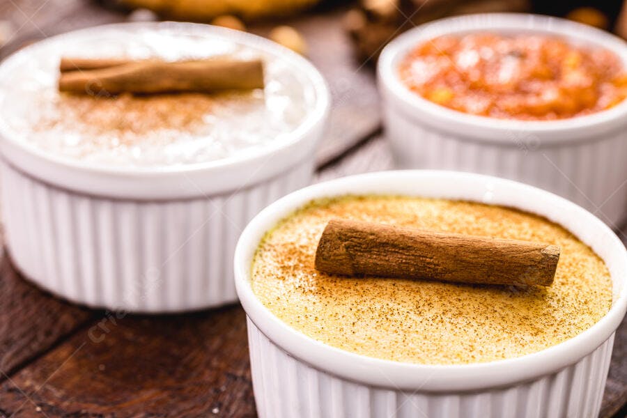 Pudim cremoso de baunilha e arroz doce com canela em pau na mesa rústica