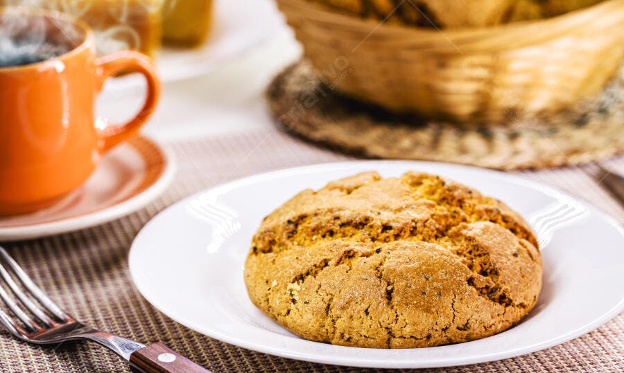 Cookie caseiro grande e dourado com café quente na mesa