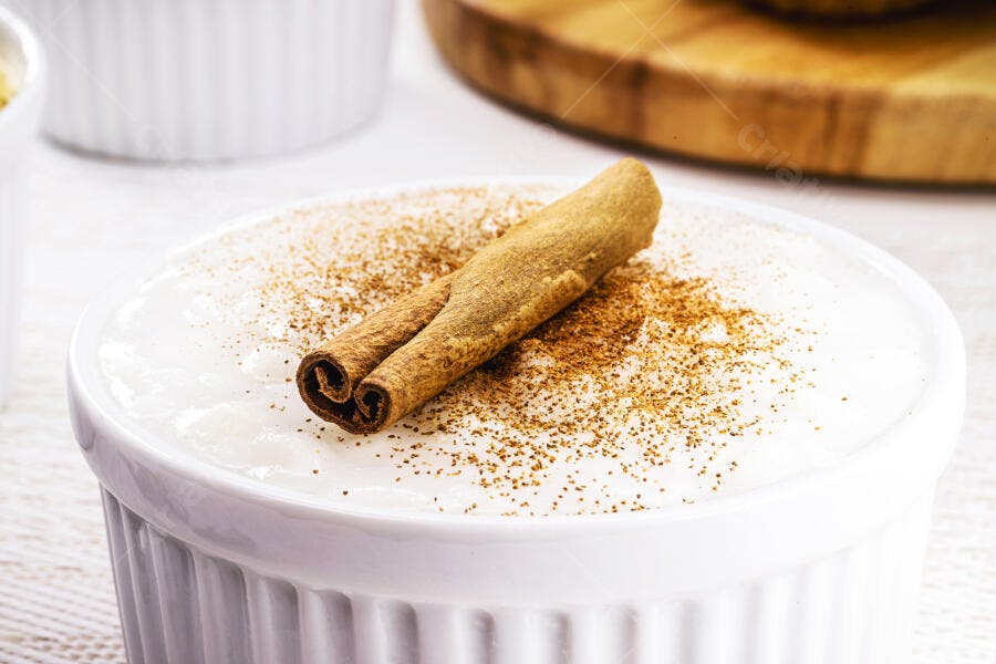 Arroz doce com canela em pó e pau de canela em tigela branca