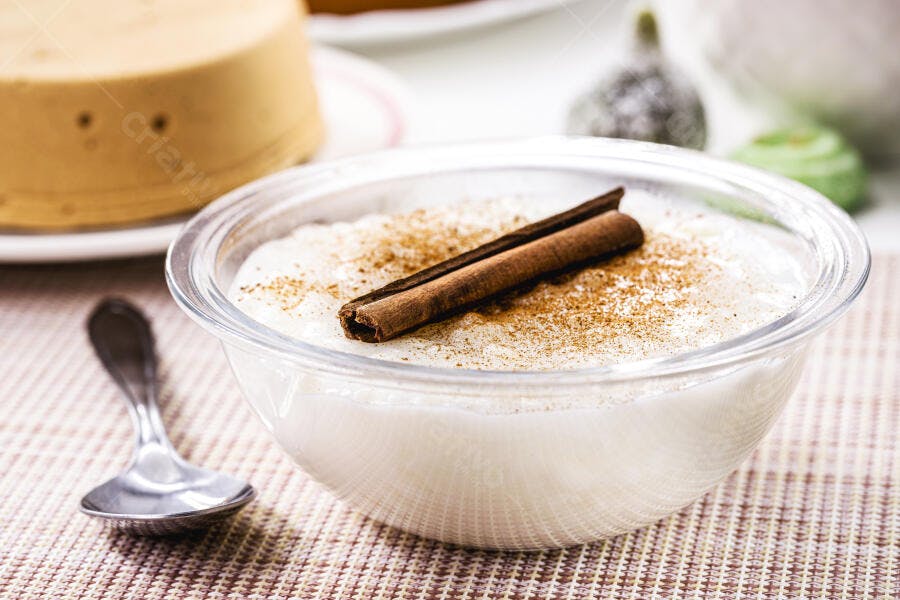 Arroz doce tradicional em tigela de vidro com canela em pó e pau