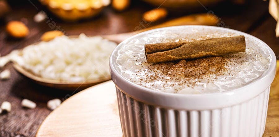 Arroz doce cremoso com canela em tigela branca sobre mesa de madeira tradicional