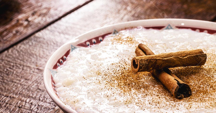 Arroz doce cremoso com canela em pau sobre mesa de madeira rústica