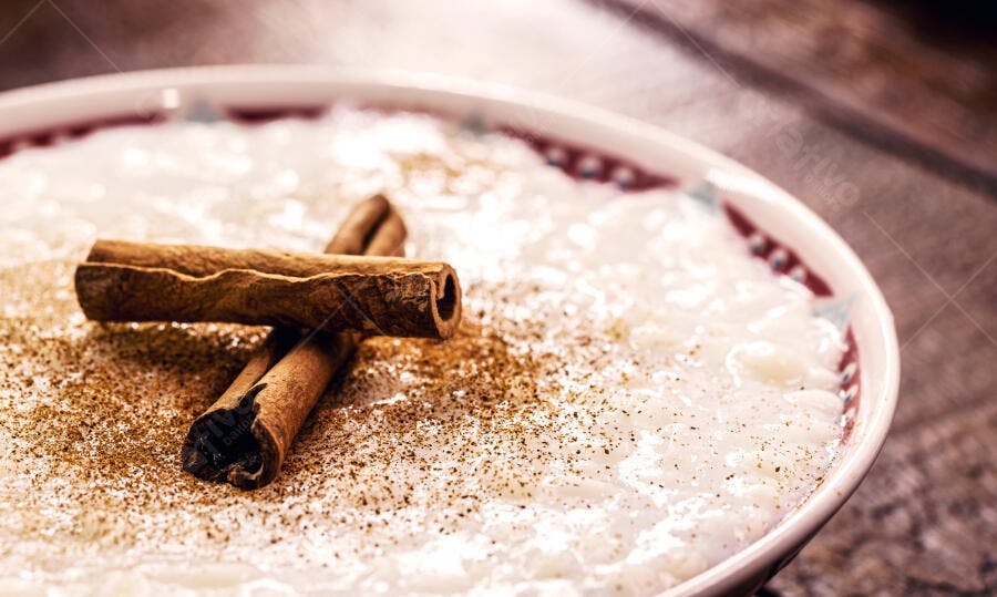 Arroz doce cremoso com canela em pau e pó em tigela decorada