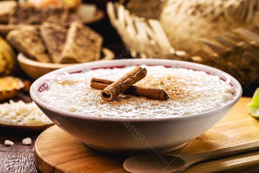 Arroz doce cremoso com canela em pau e pó sobre mesa de madeira rústica