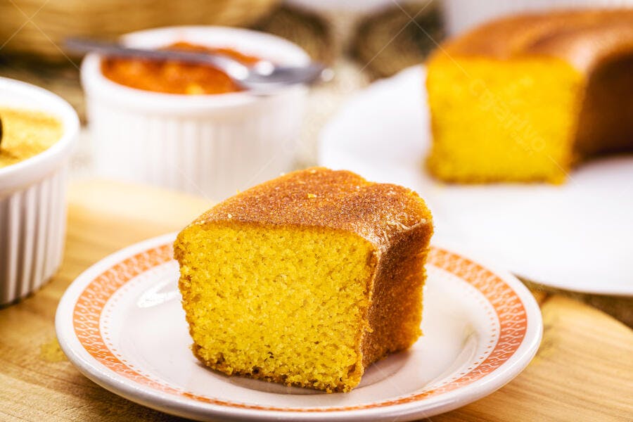 Fatia de bolo de milho em prato rústico sobre tábua de madeira