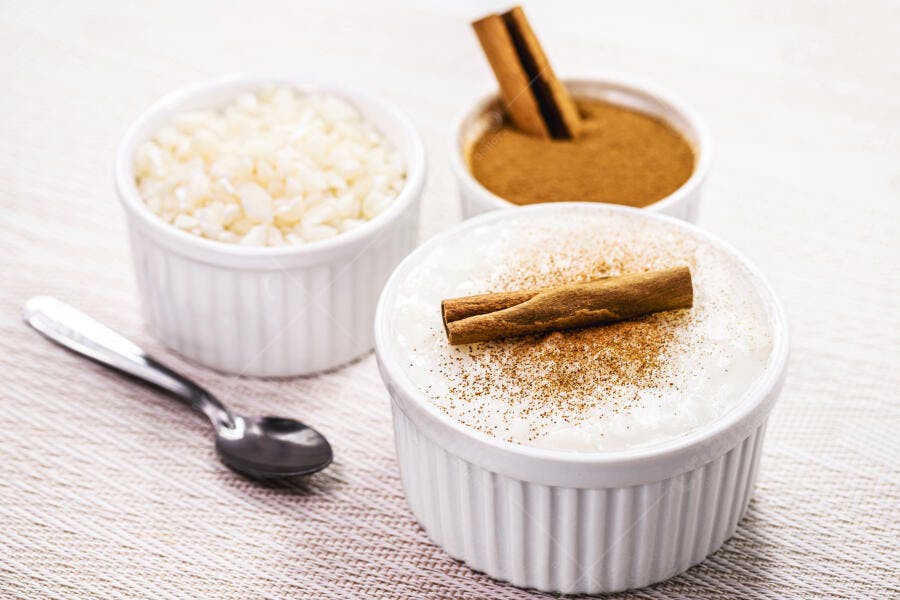 Arroz doce tradicional com canela em pau e em pó servido em ramekins brancos