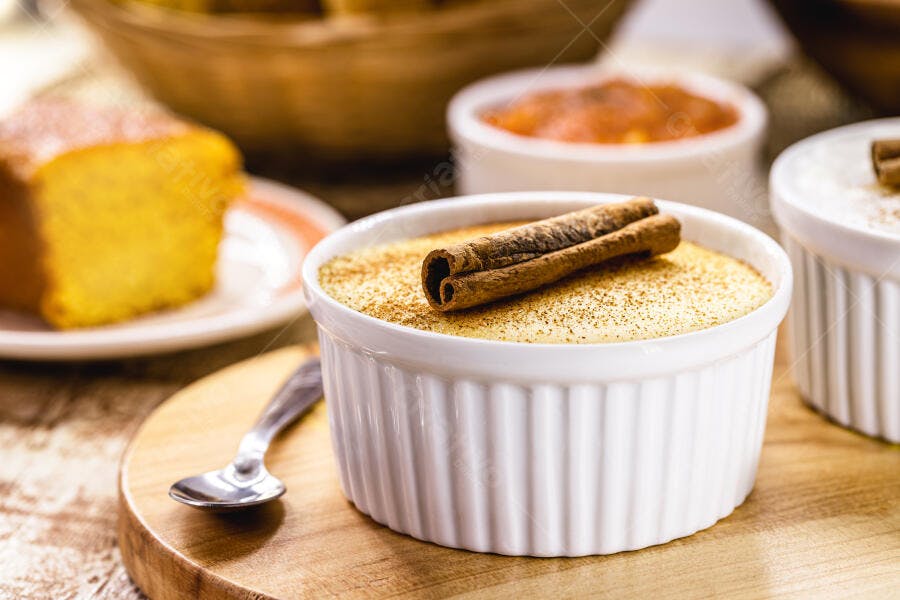 Arroz doce cremoso com canela em pau e bolo de fubá em mesa rústica