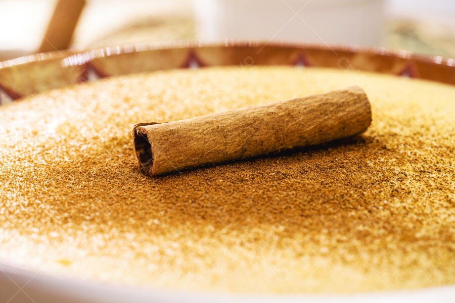 Canela em pau sobre doce cremoso polvilhado com canela em pó tons quentes de marrom