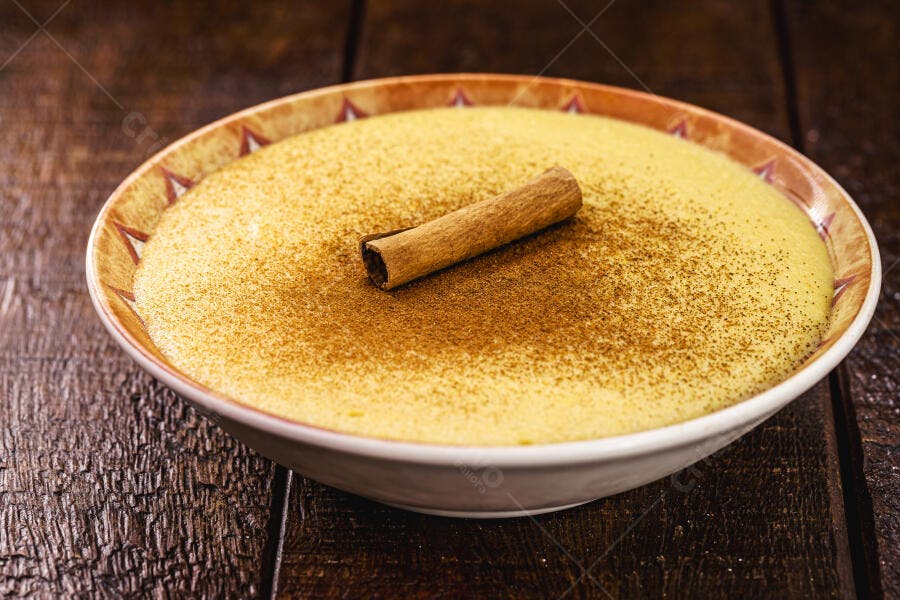 Curau de milho doce com canela em pau e pó em tigela rústica