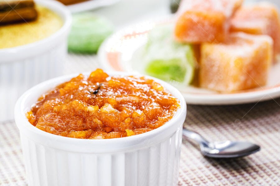 Doce de abóbora caseiro em ramekin branco com doces de frutas sortidos e colher