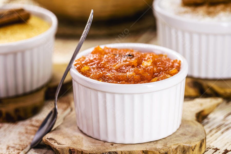 Doce de abóbora cremoso em ramekin branco sobre mesa de madeira rústica com colher