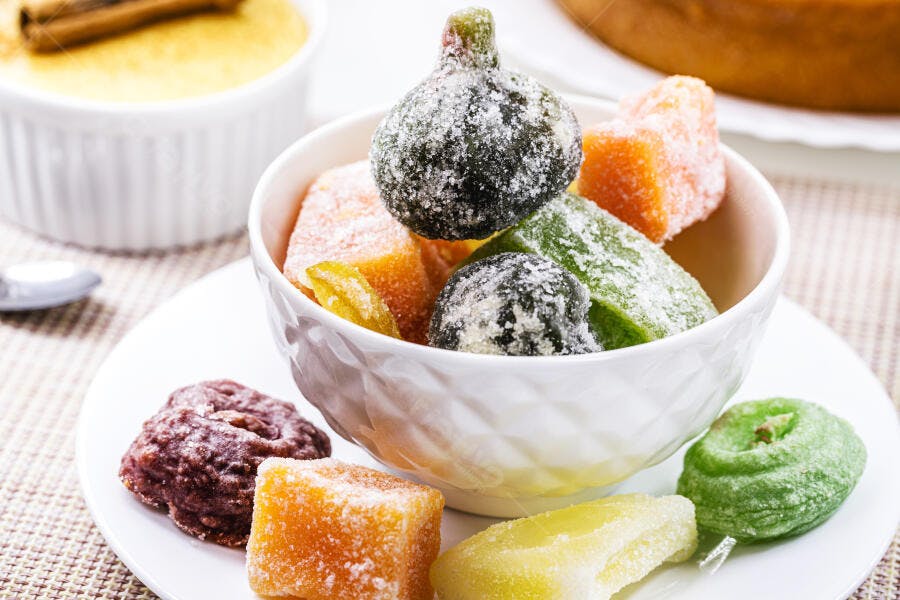 Frutas cristalizadas variadas coloridas em tigela branca sobre mesa