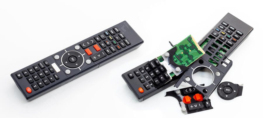 Controle remoto cinza intacto e outro desmontado com placa verde em fundo branco