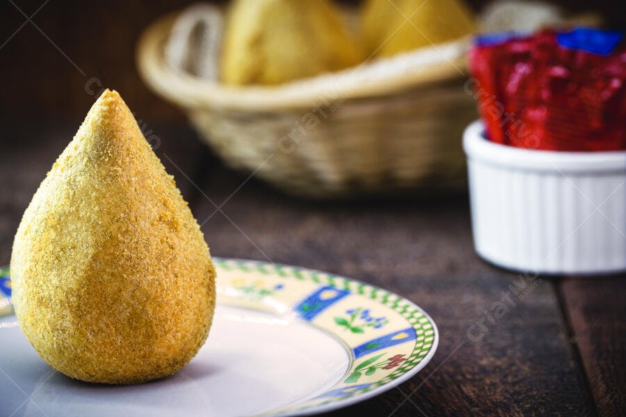 Coxinha dourada crocante em prato decorado salgado brasileiro com molhos e cesto