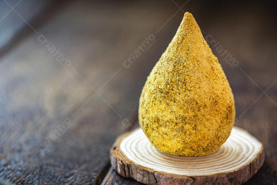 Coxinha dourada crocante em base de madeira rústica