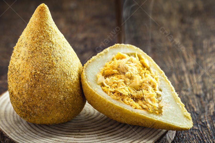 Coxinha de frango frita com recheio cremoso em tábua de madeira rústica