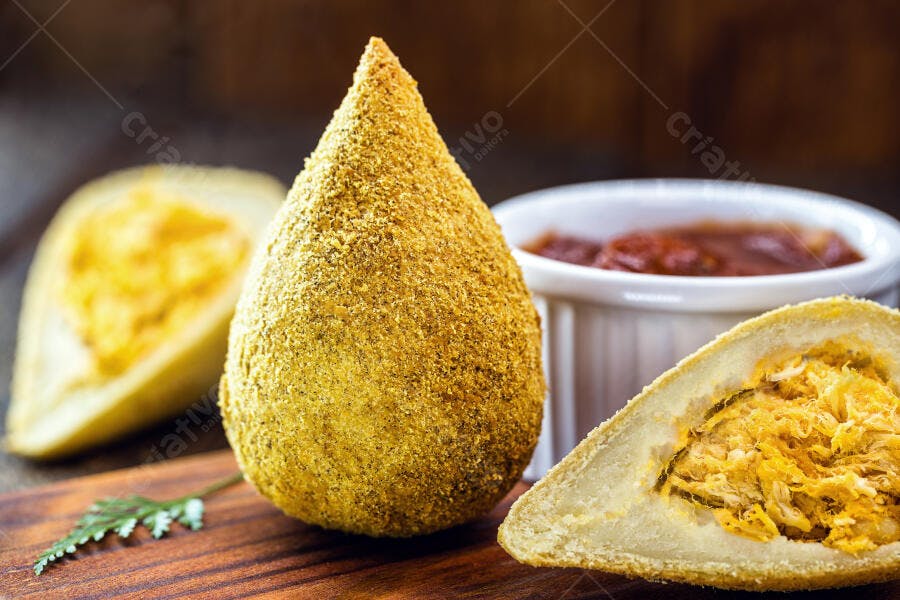 Coxinha de frango brasileira crocante com molho e recheio visível