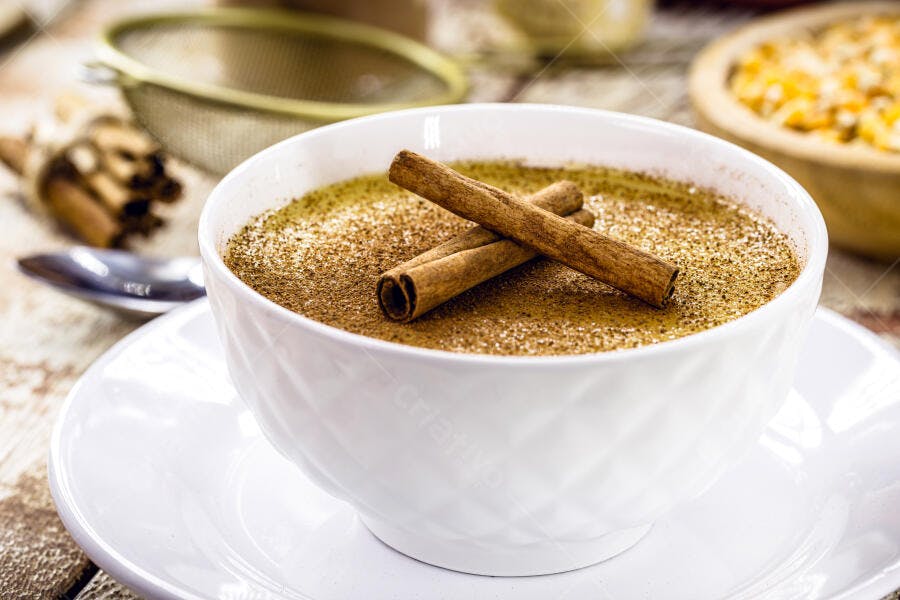 Curau de milho doce com canela em tigela branca na mesa rústica