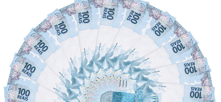 Cédulas de 100 Reais brasileiras espalhadas em formato de leque sobre fundo branco