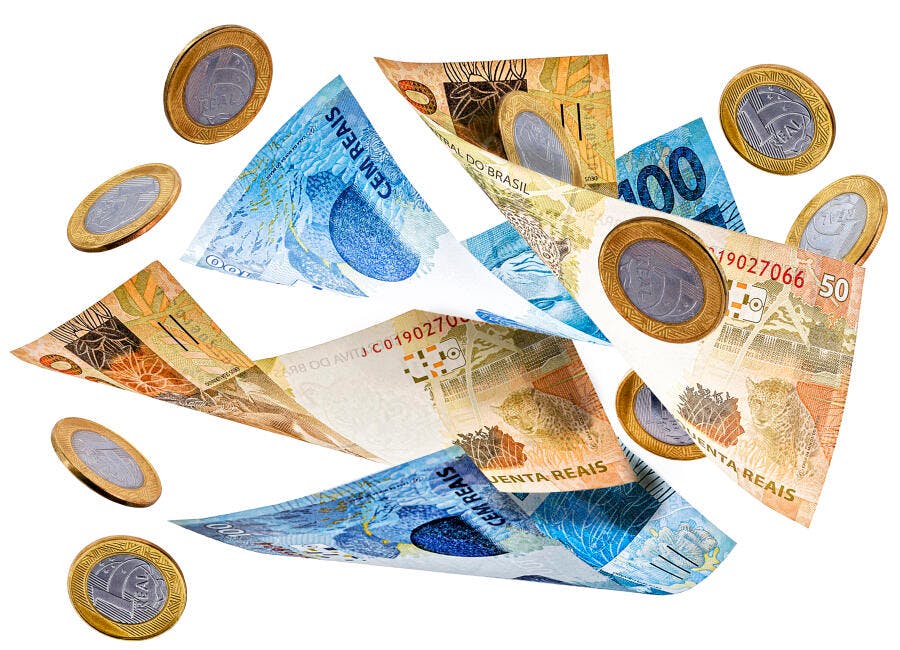 Cédulas de reais e moedas brasileiras flutuando em fundo branco