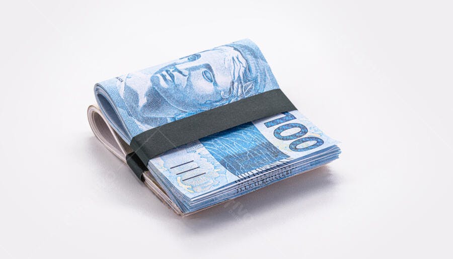 Cédulas de cem reais azuis amarradas com elástico em estúdio branco