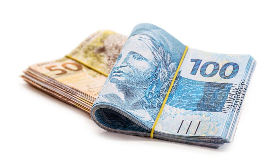 Notas de cem e cinquenta reais amarradas com elástico em fundo branco
