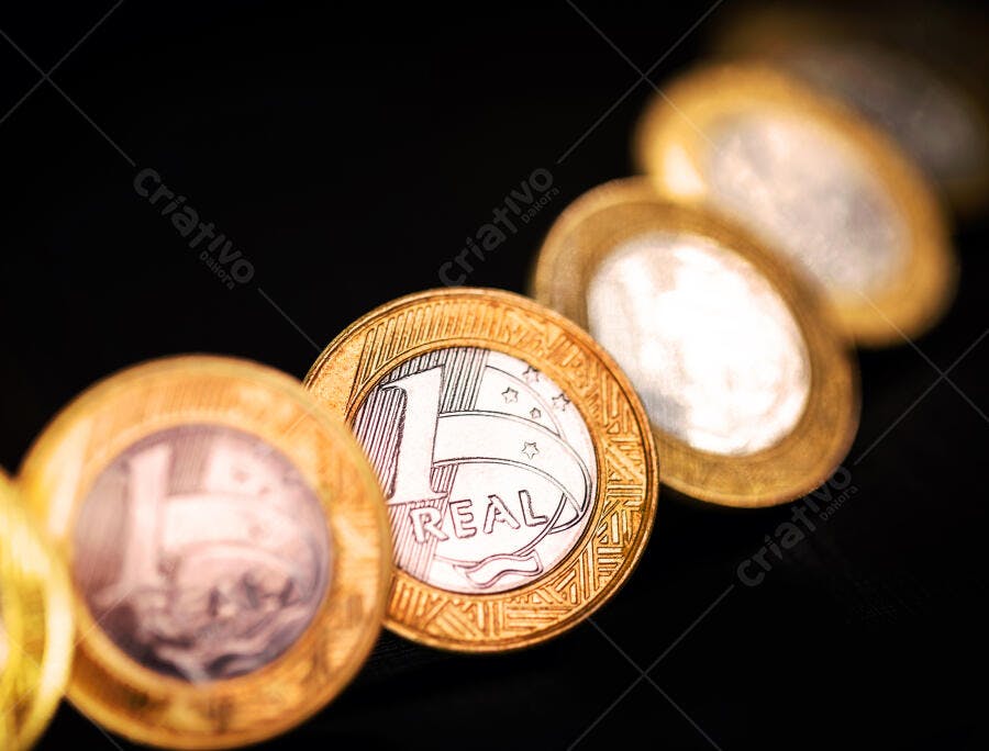 Moedas de 1 Real brasileiro douradas e prateadas em fundo escuro closeup