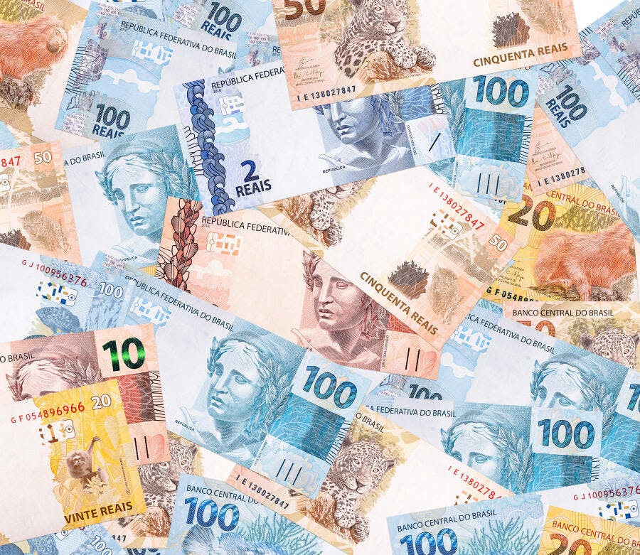 Dinheiro brasileiro notas de reais coloridas espalhadas fundo branco