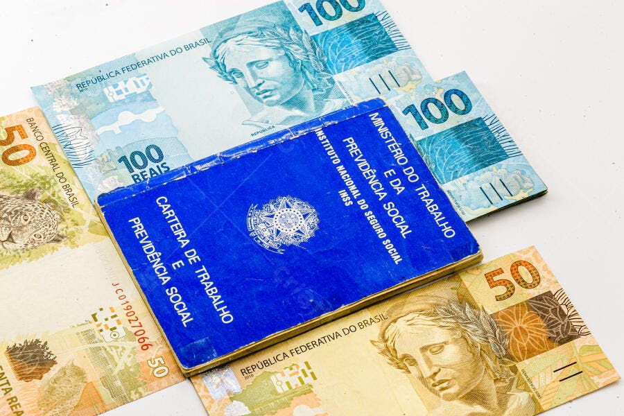 Carteira de Trabalho azul com cédulas de 100 e 50 Reais Brasileiros