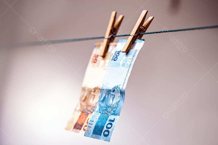 Notas de 100 e 50 Reais brasileiros penduradas no varal com prendedores de madeira