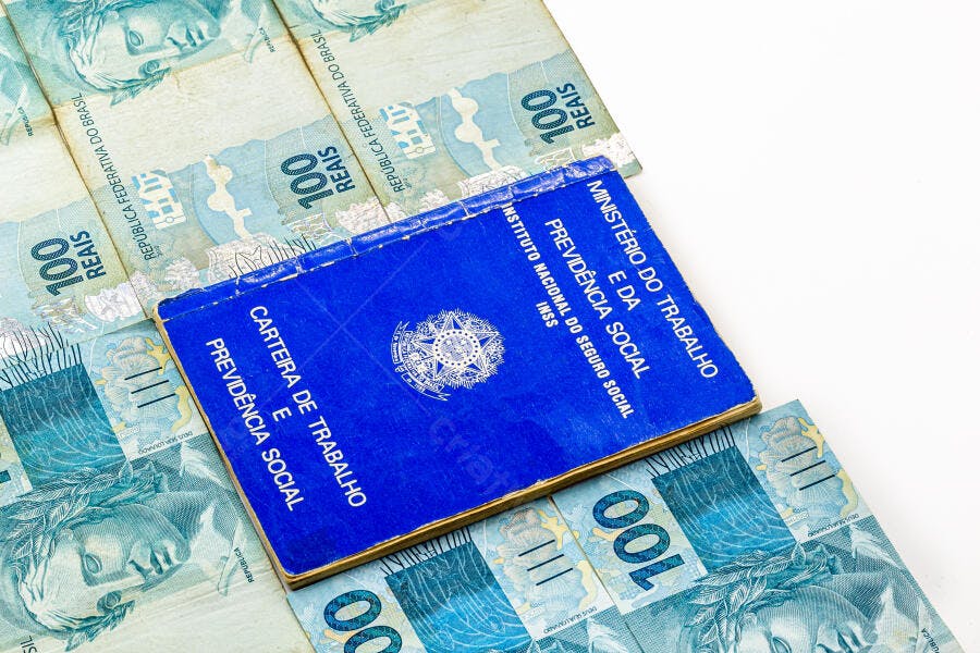 Carteira de Trabalho azul sobre notas de 100 Reais dinheiro brasileiro previdência social