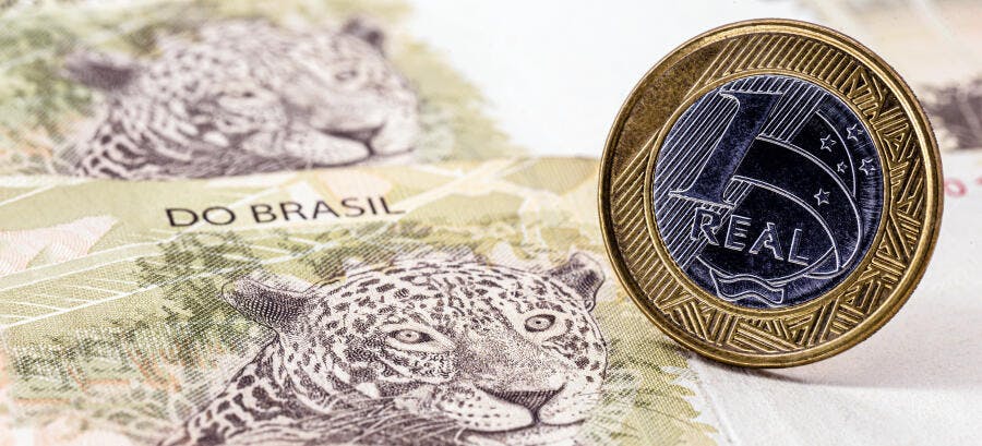 Moeda de 1 Real brasileira dourada e prateada sobre notas de onça-pintada