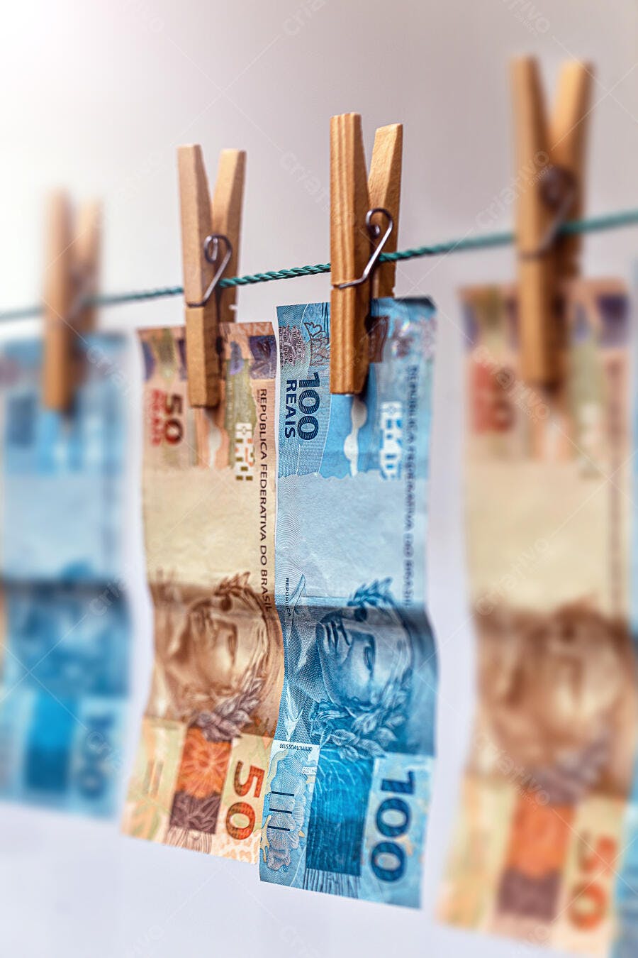 Notas de Real brasileiras de 100 e 50 penduradas em varal com prendedores de madeira