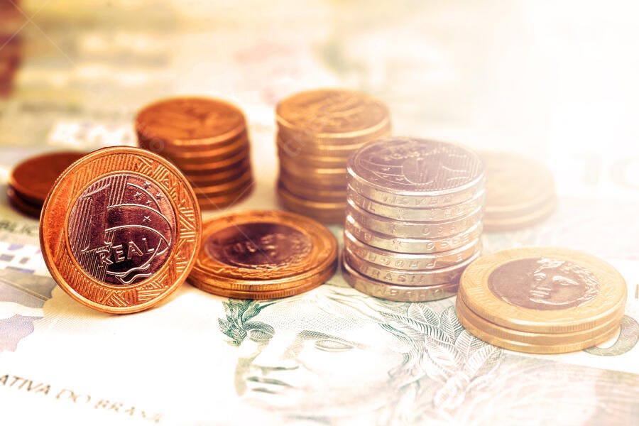 Moedas de Real e notas douradas sobre cédulas brasileiras