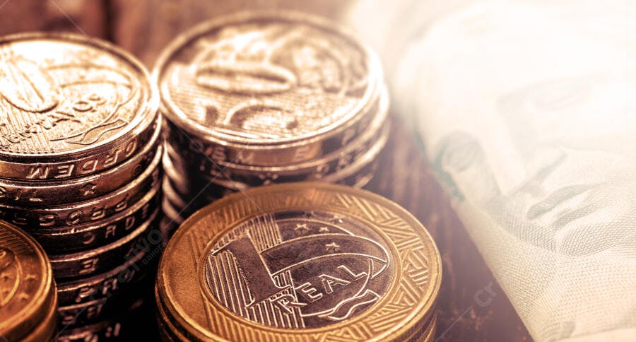 Moedas de Real empilhadas e notas de dinheiro com luz suave