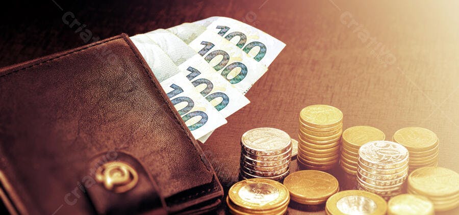 Carteira marrom com notas de euro e moedas brasileiras em mesa escura