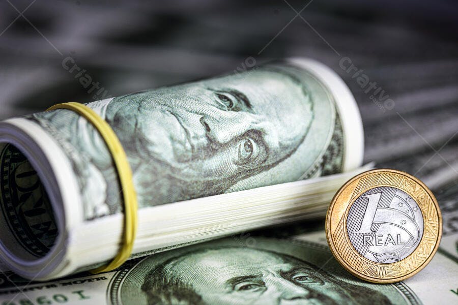 Rolo de notas de dólar e moeda de 1 real brasileiro em cenário financeiro